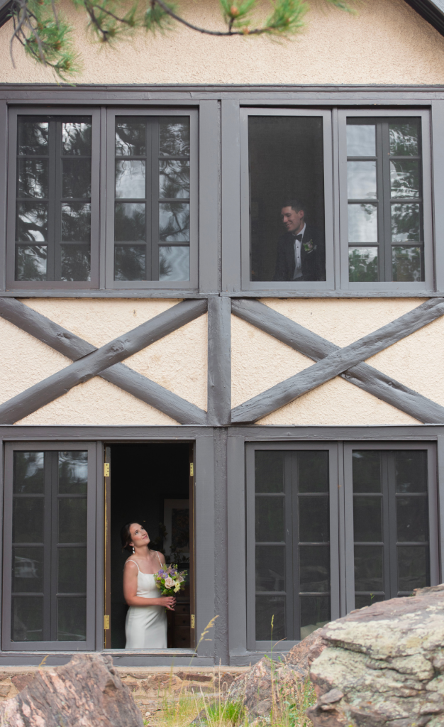 Bride and groom peeking out of windows of old building